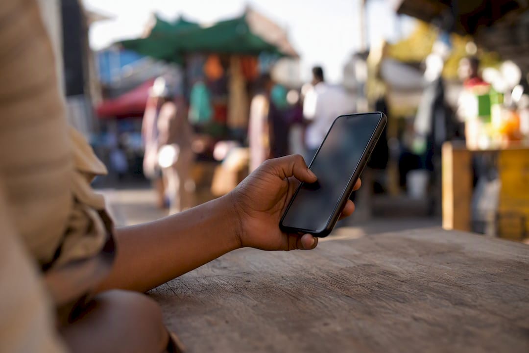 Hand tapping smartphone in busy urban setting