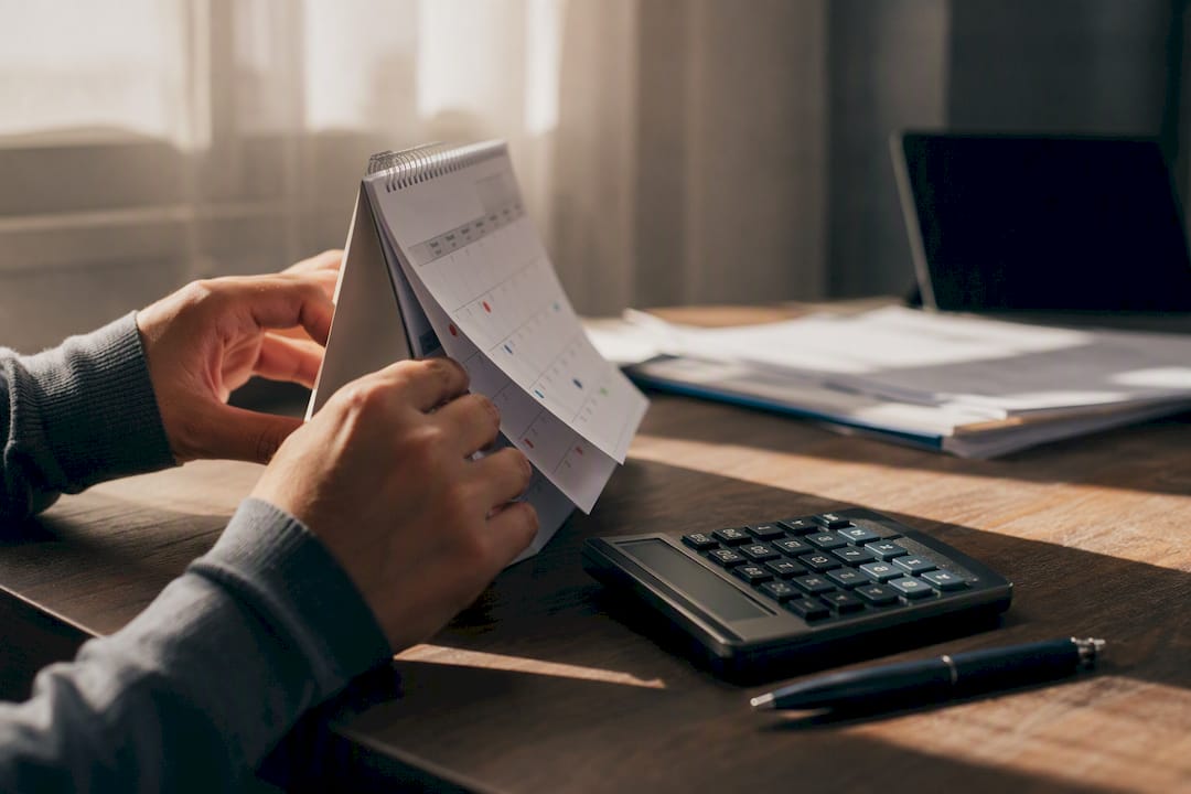 Mano che segna una data sul calendario vicino alla calcolatrice