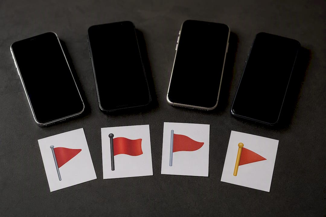 Four phones with different red flag emoji styles concept