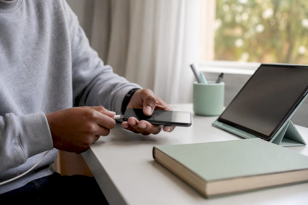 Hands plugging phone charger near laptop