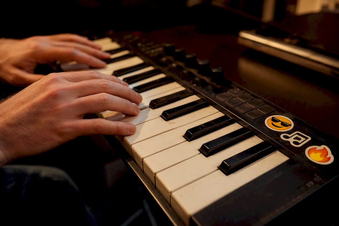 Hands playing piano keyboard with emoji stickers nearby