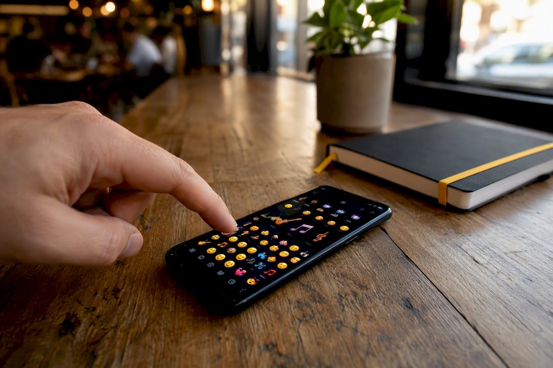 Hand selecting music emojis on smartphone