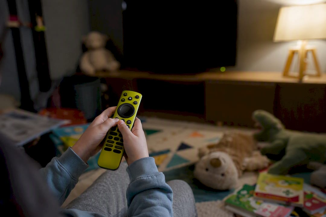 Ręce trzymają pilota, wybierając dziecięce VOD