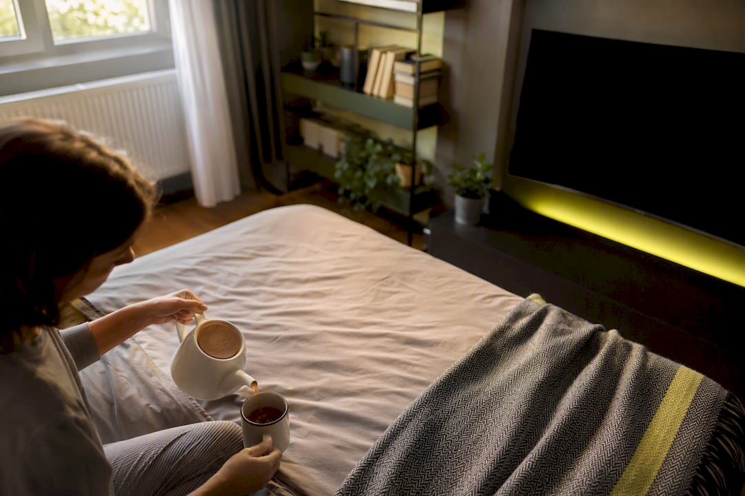 Persona che versa il tè nel soggiorno con la TV spenta