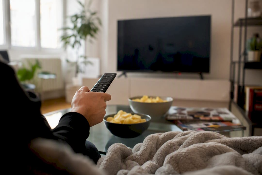 Mani che tengono il telecomando scegliendo un film in TV