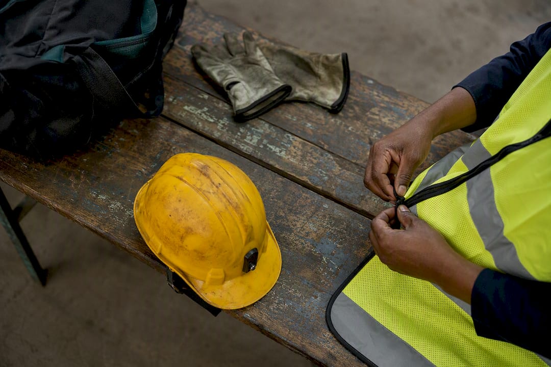 Hands adjusting mining safety vest and helmet