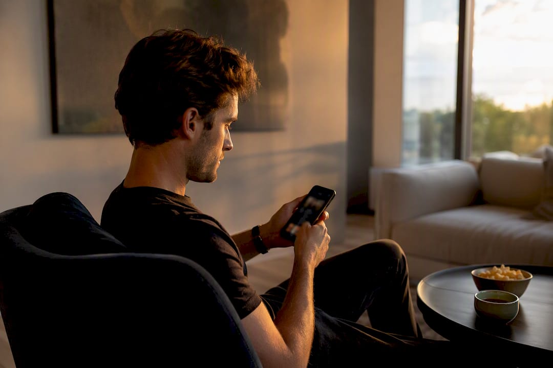 Mani che tengono uno smartphone pronte a navigare tra i contenuti in streaming