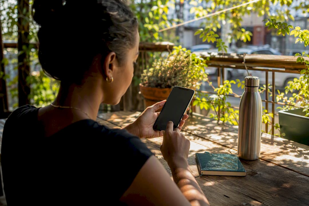 Hands typing on smartphone at wooden table