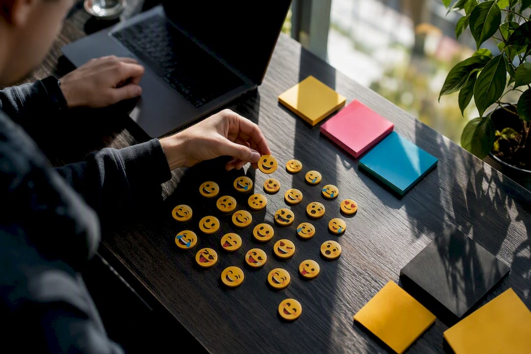 Hand placing emojis on workspace for brand matching