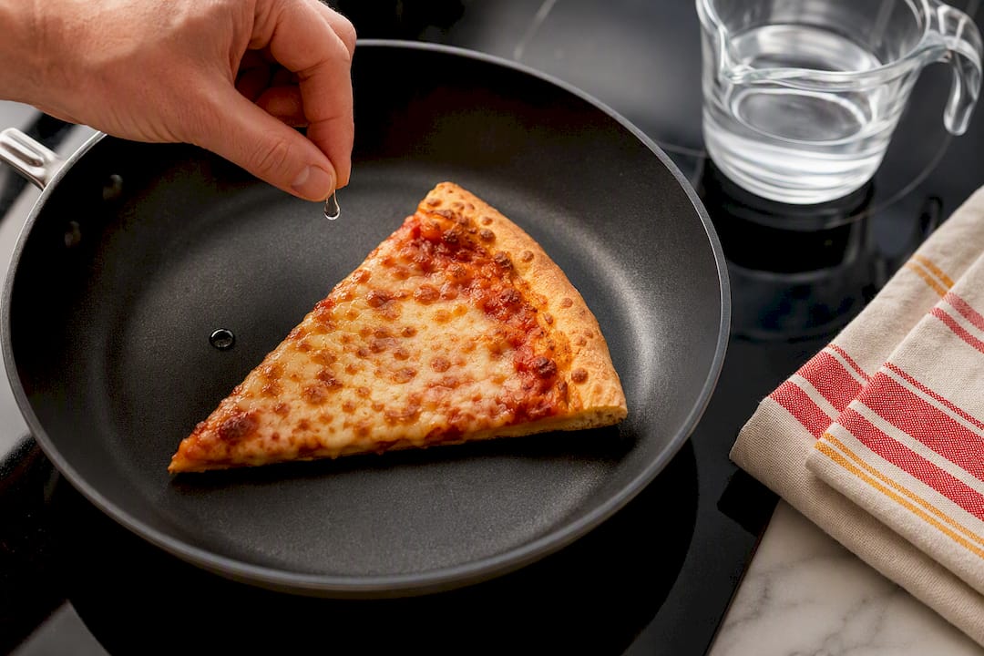 Pizza slice with water drop in skillet