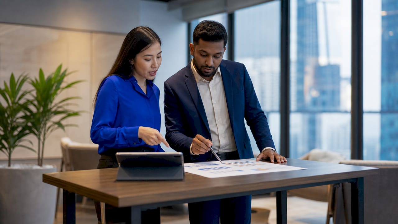 Two professionals reviewing financial reports at meeting table