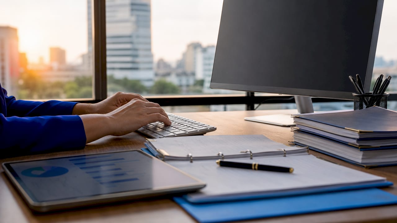 Hands typing payroll documents in office cubicle