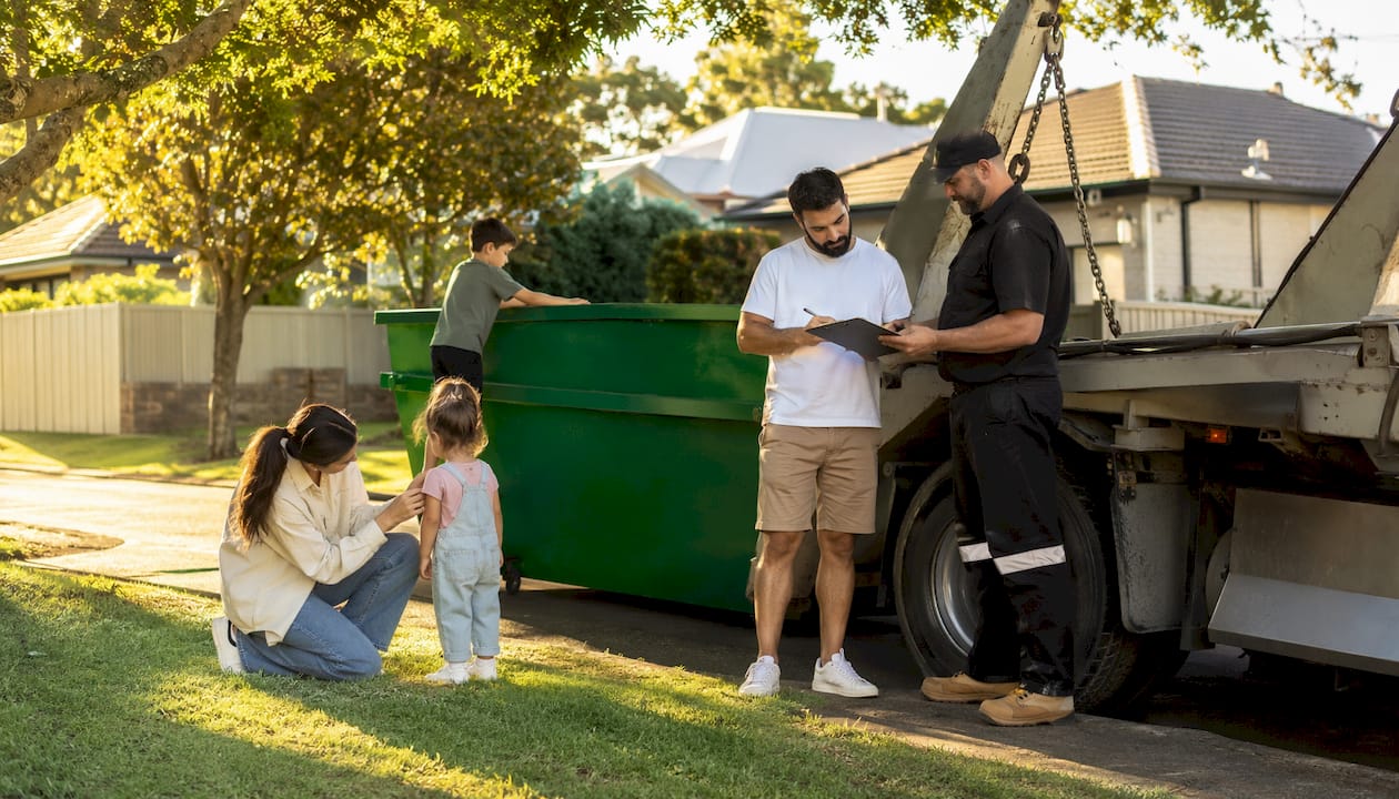 Family receiving dirt skip bin delivery outdoors