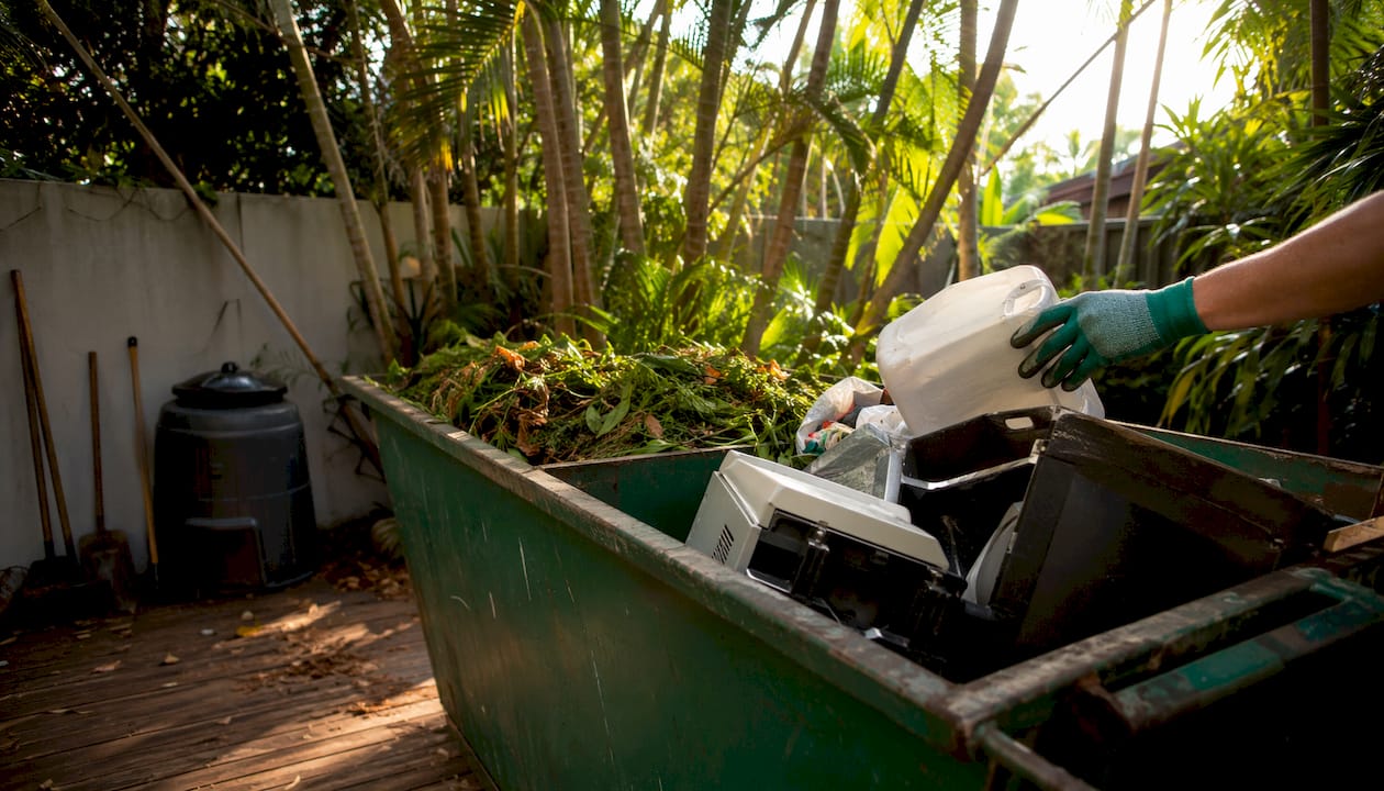 Hands loading separate waste types into skip bin