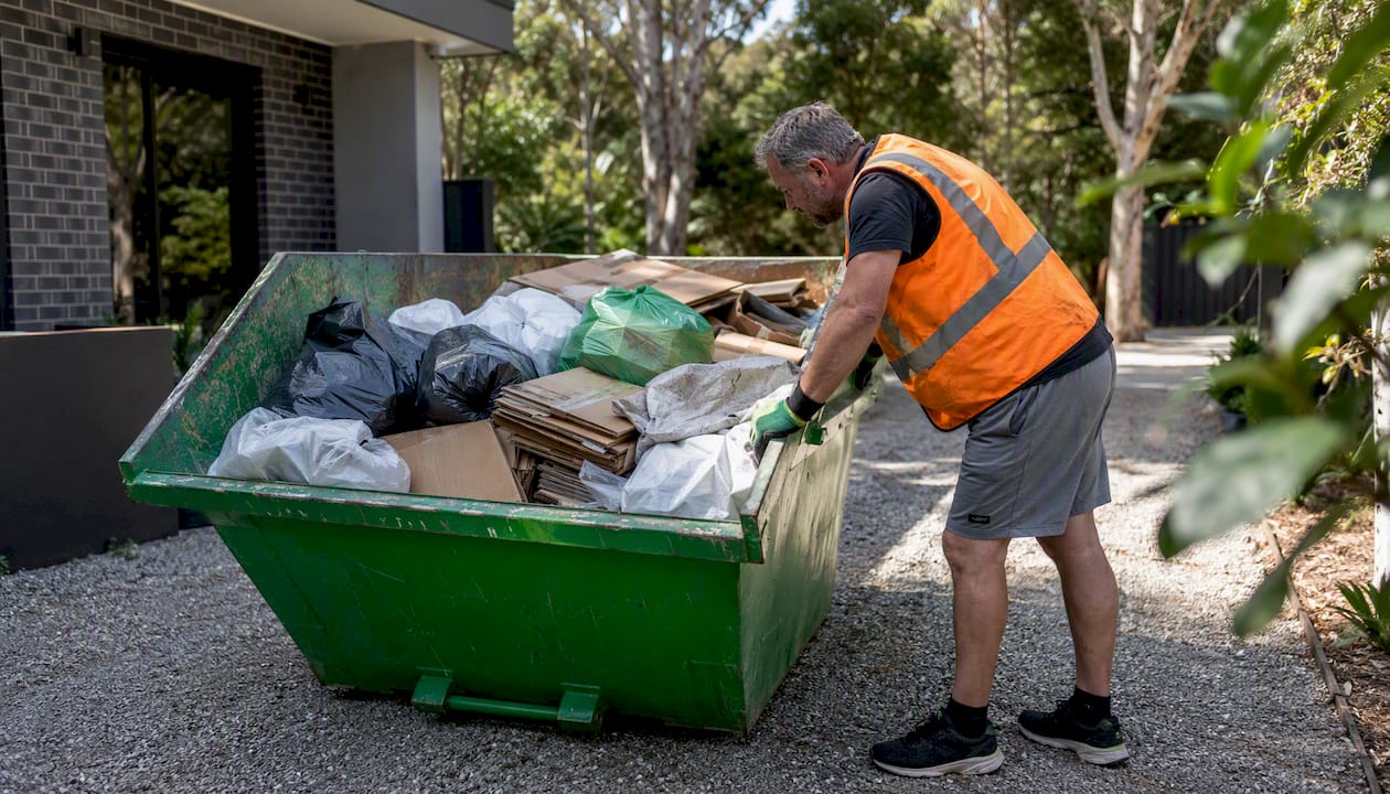 Man checking fill level in mini skip bin