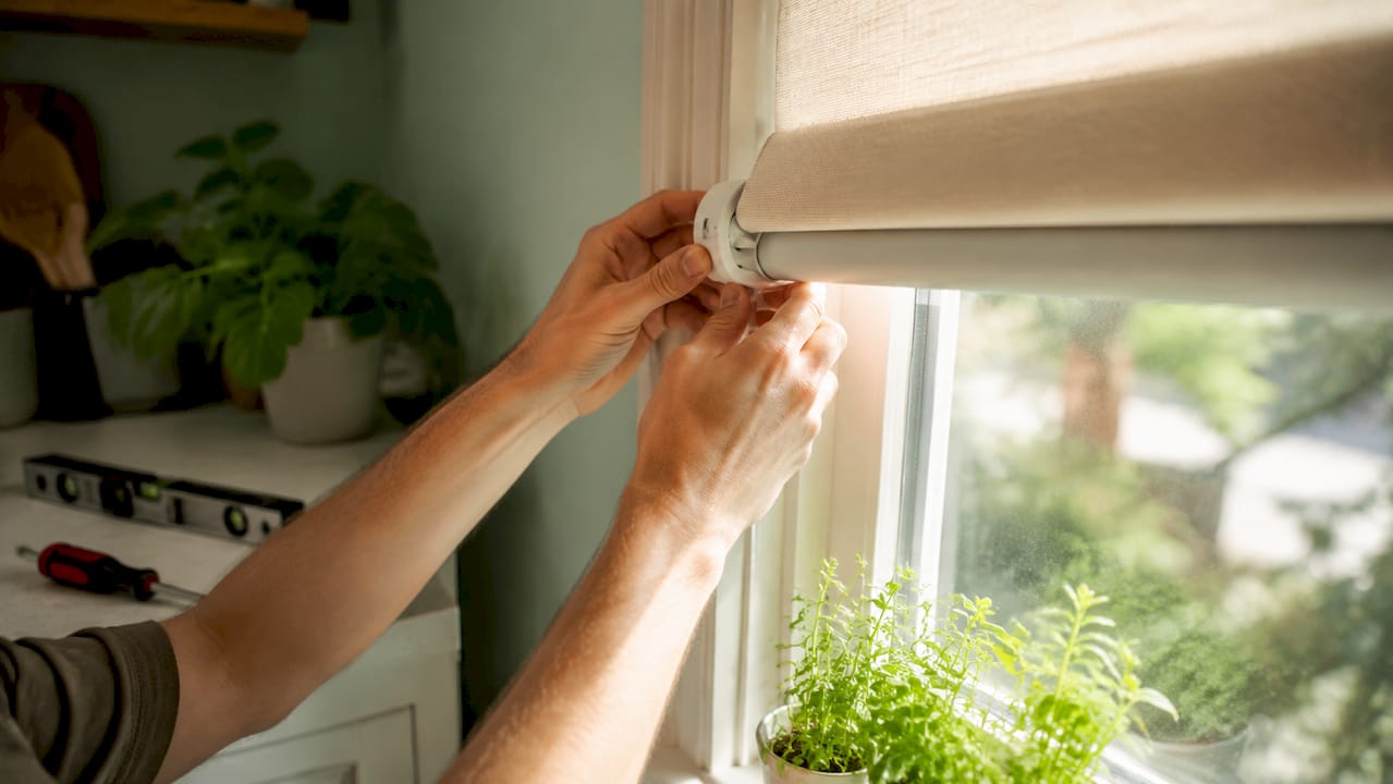 Hands installing cordless roller shade in renter's apartment