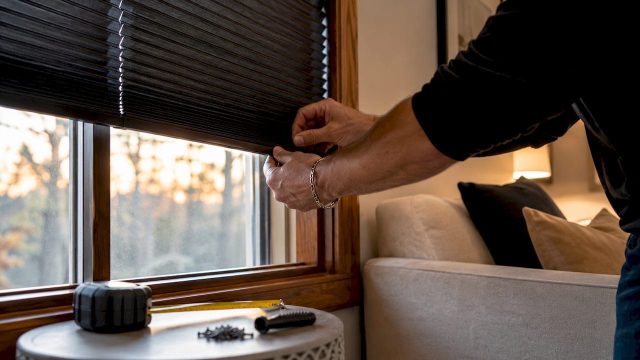 Hands installing black cellular shades