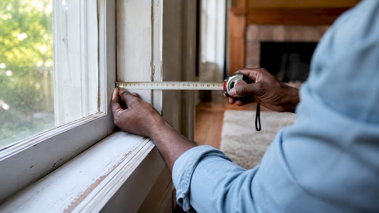 Hands measuring window frame depth for blinds