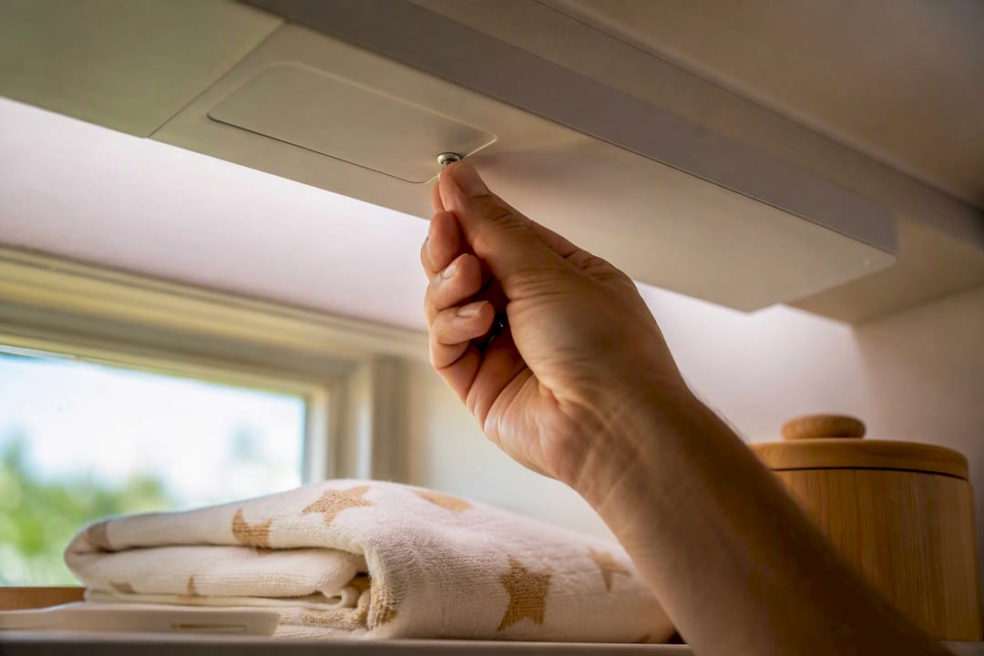 Hand securing a motorized shade battery compartment