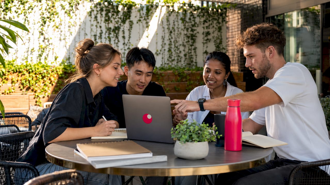 Marketing team collaborating around laptop at table