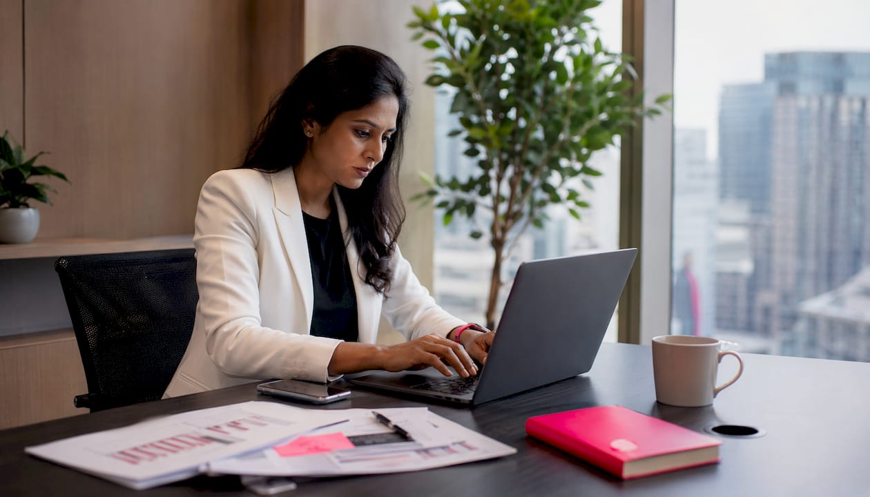 Digital marketer working on laptop at sunlit office desk