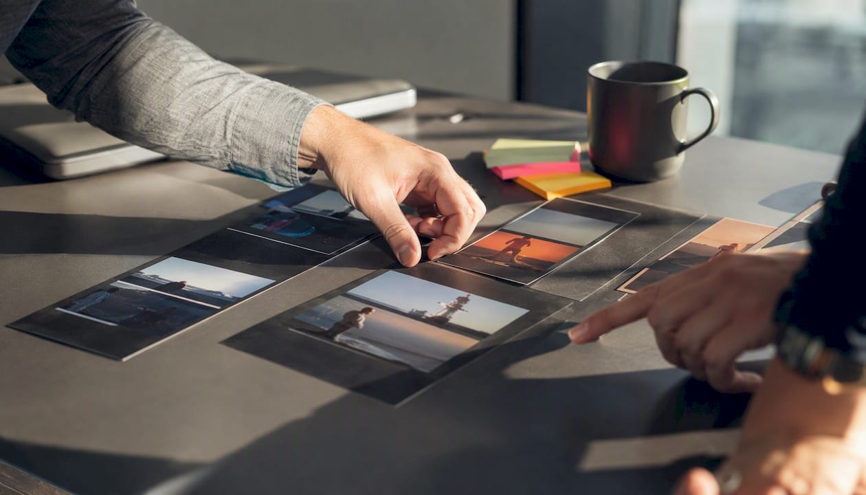 Hands arranging video ad thumbnails during testing