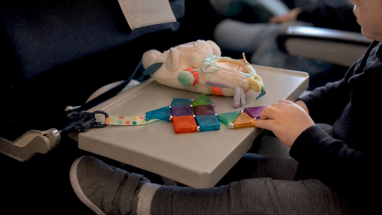 Magnetic toddler toy tethered to airplane seat