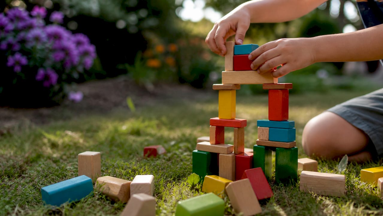 Child stacking wooden blocks in playroom