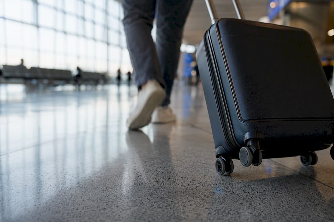 Wheeled suitcase rolling on airport floor
