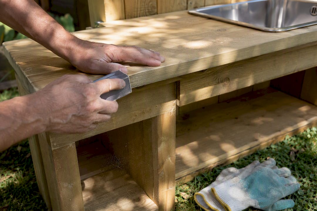 Hands sanding mud kitchen wooden countertop edges