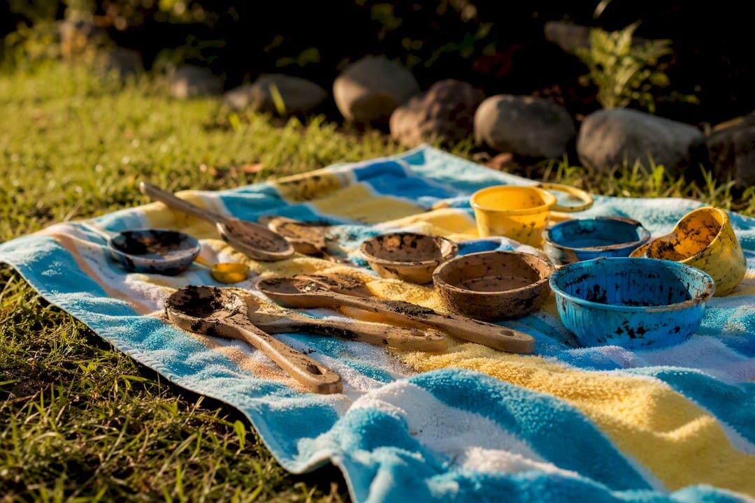 Mud kitchen tools drying on towel outdoors