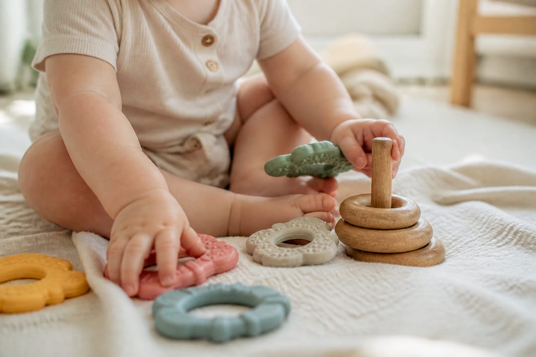 Infant hands touching wooden sensory toys