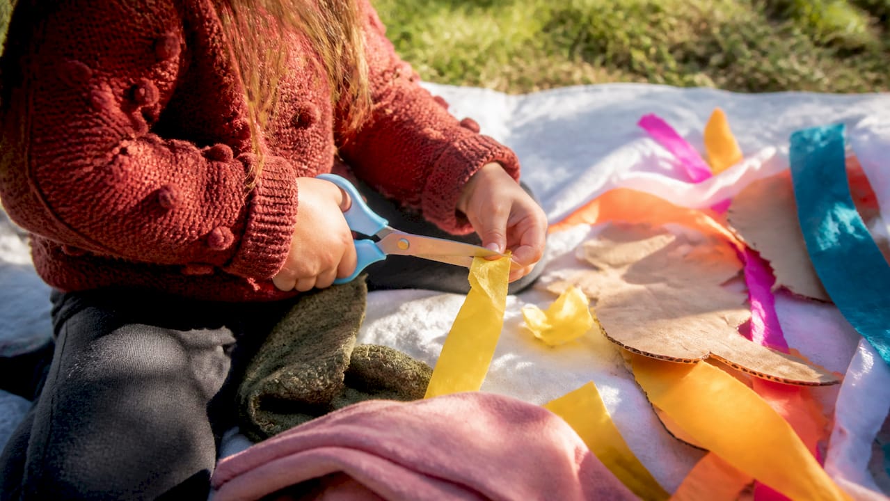 Child hands testing safe scissors with different materials