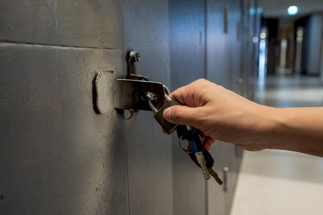 Hand checking a worn hostel locker hasp