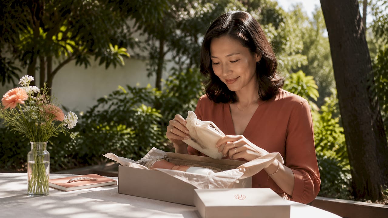 Woman opening employee gift box at home desk
