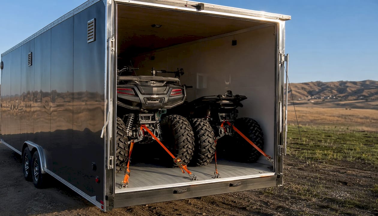 Enclosed trailer with secured ATVs inside outdoors