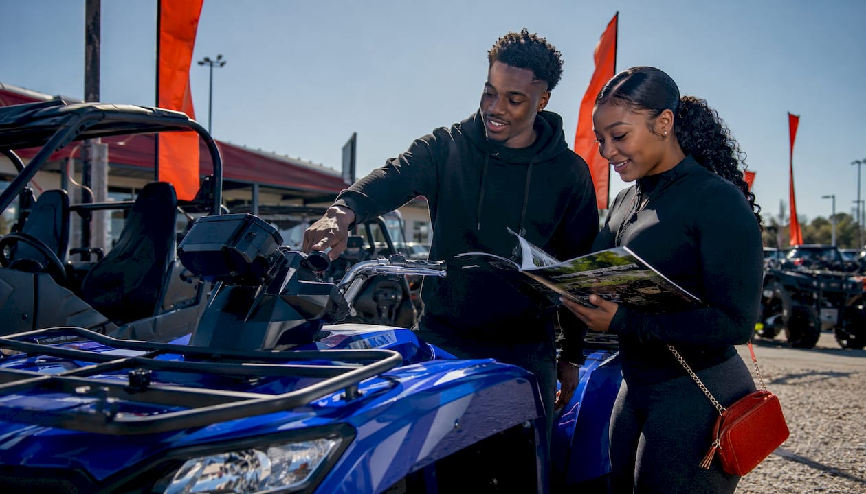Couple inspecting Yamaha ATV in dealership showroom