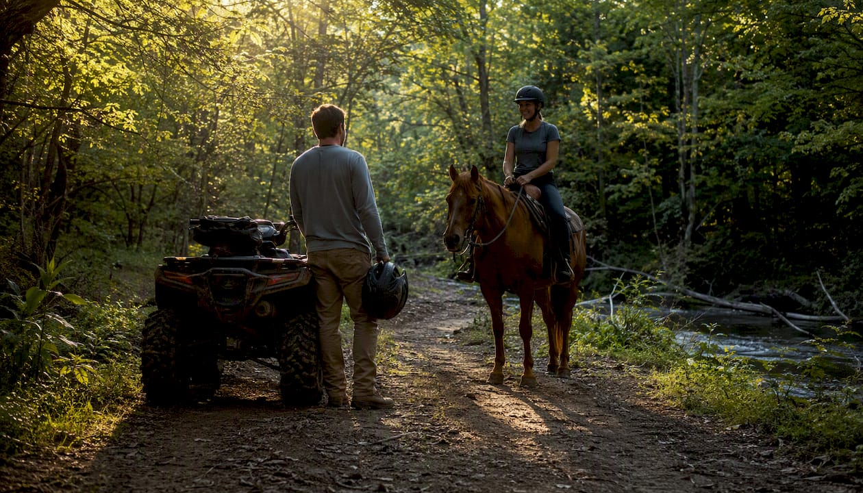 ATV rider stopped and yielding to horse on forest trail