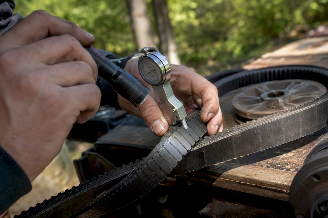 Hands checking CVT belt condition with tools