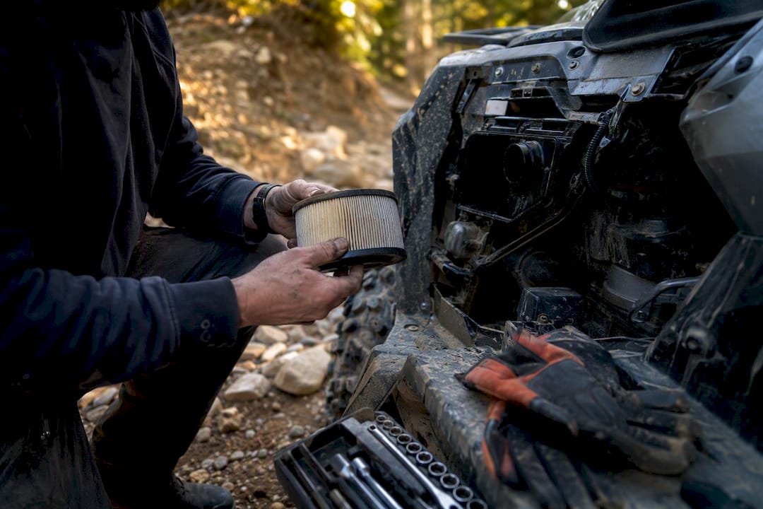 Rider inspecting ATV suspension outdoors