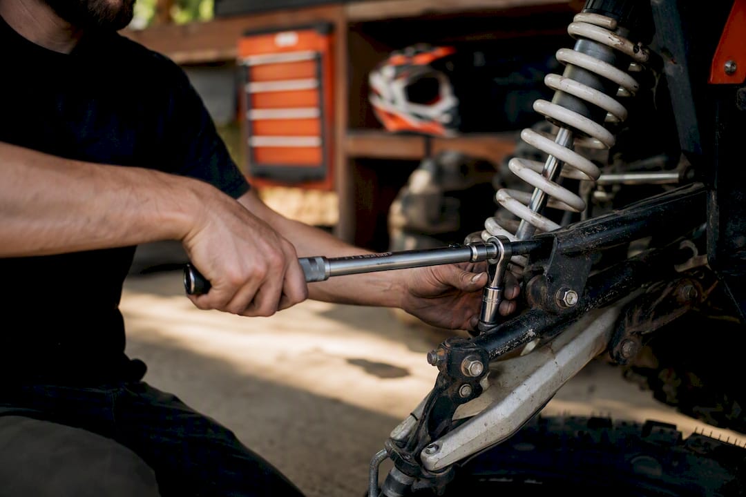 Mechanic tightening suspension part on off-road vehicle