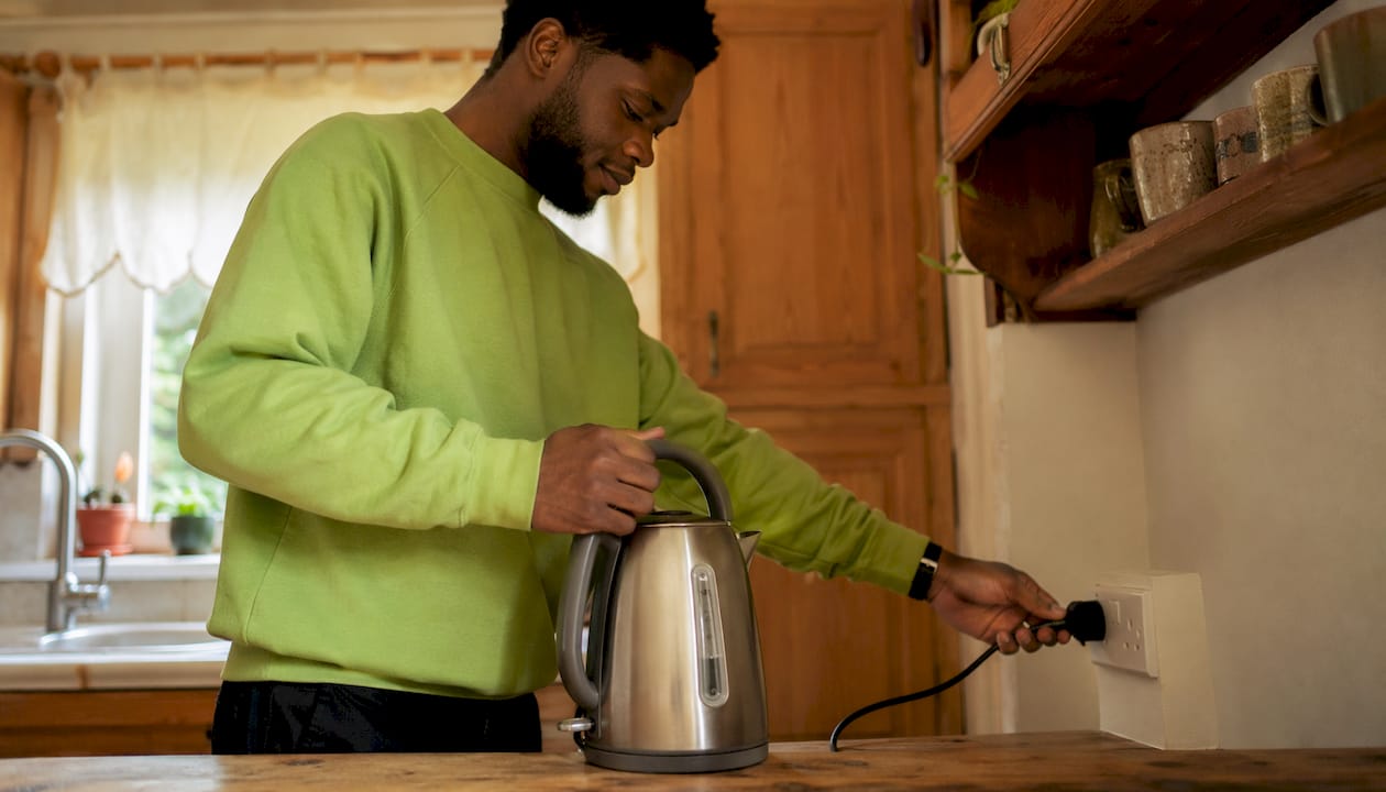 Man plugging kettle away from kitchen sink water