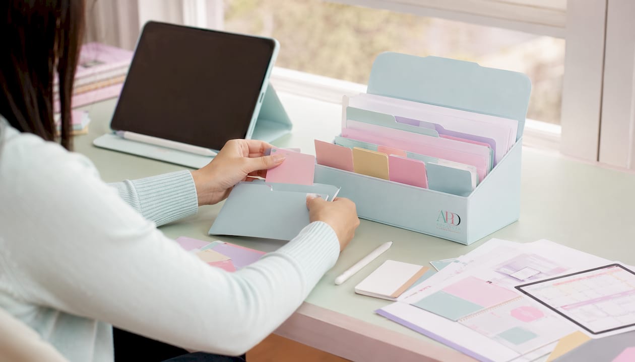 Hands packaging digital files on pastel desk
