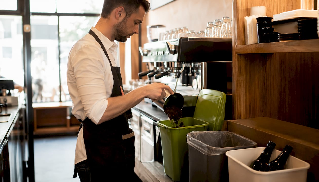 Barista sorting waste at cafe bin station
