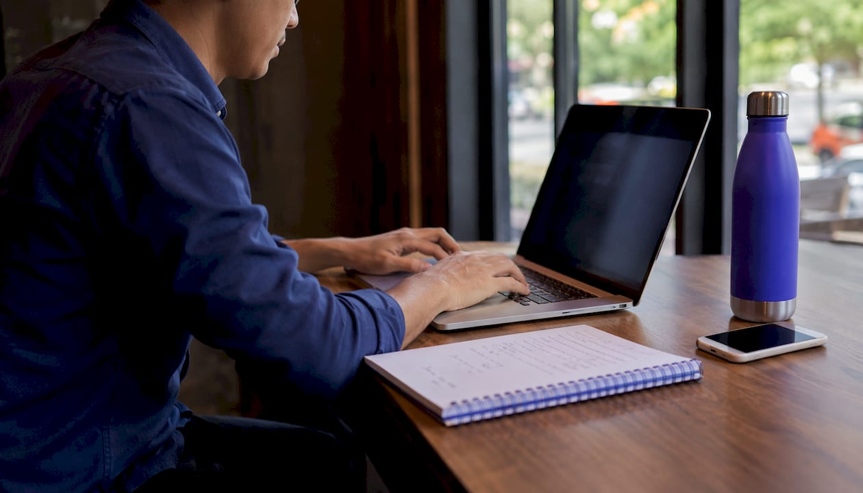 Hands typing meeting notes in office