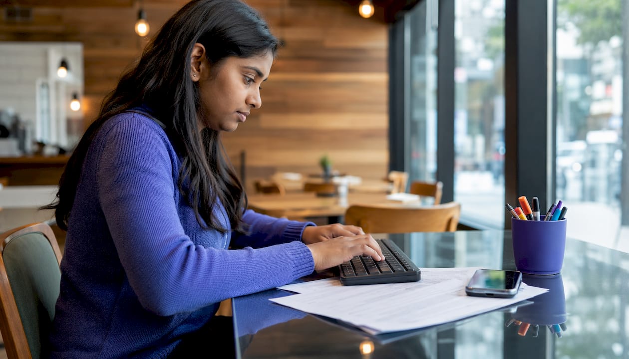Hands typing on keyboard near coaching transcripts