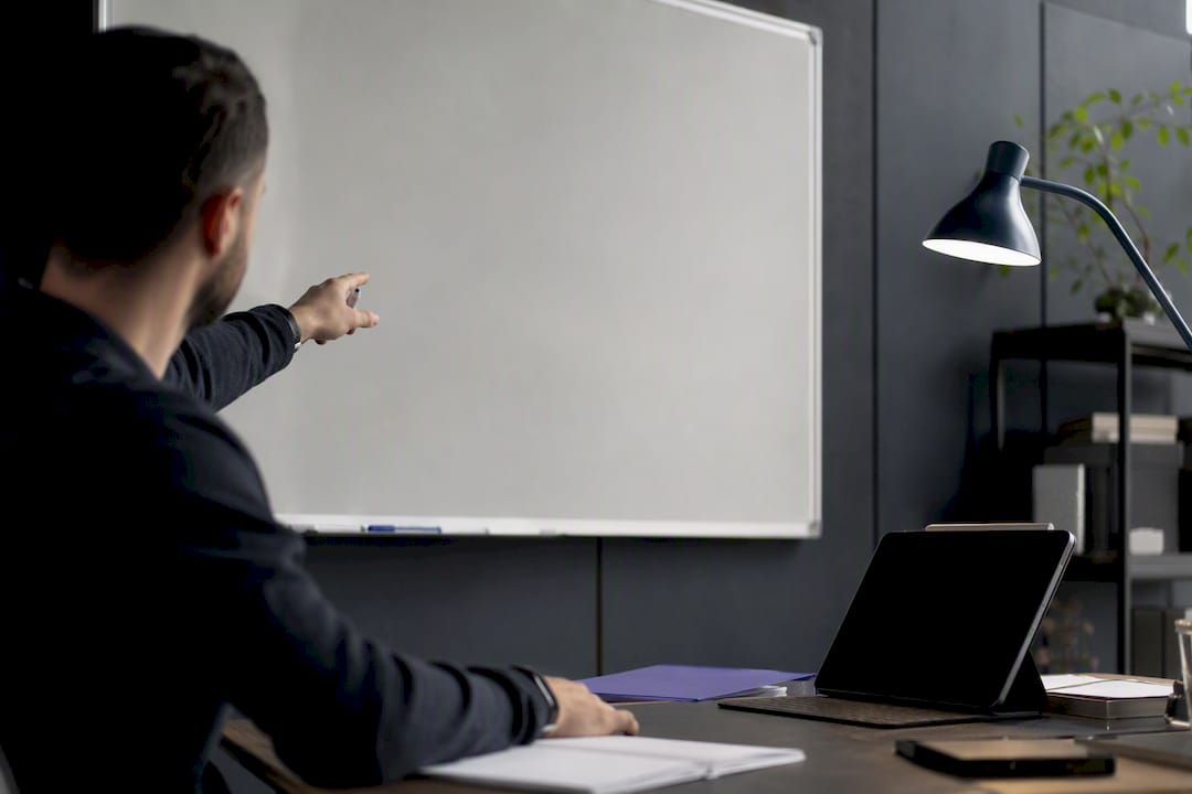 Hand pointing near blank notebook on desk