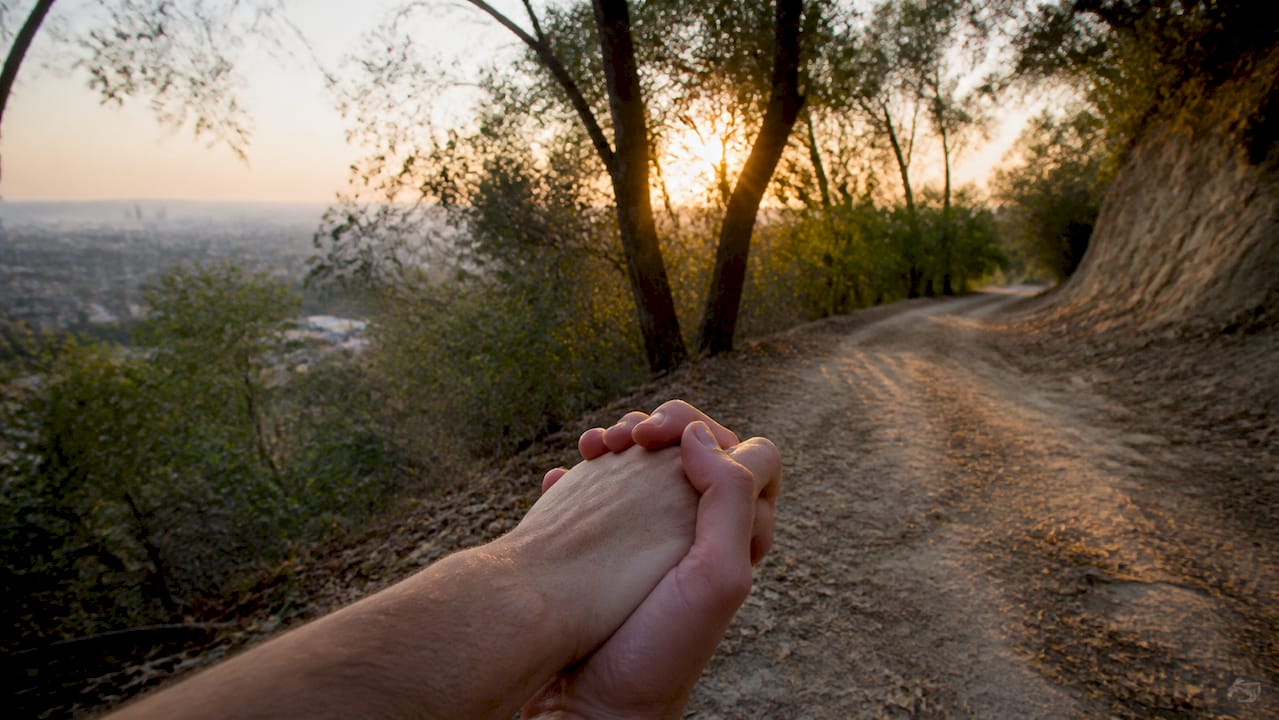 Couple holding hands walking on Santa Monica Pier at sunset