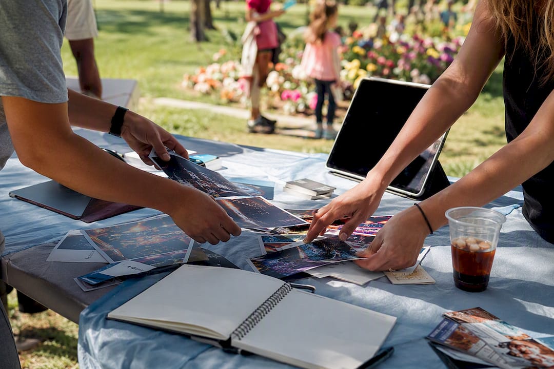 Hands organizing event submission materials on table