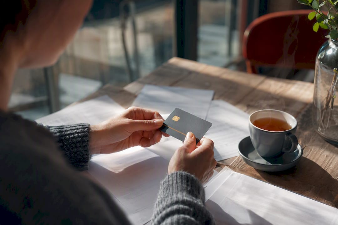 Hands holding bank card over bank statements